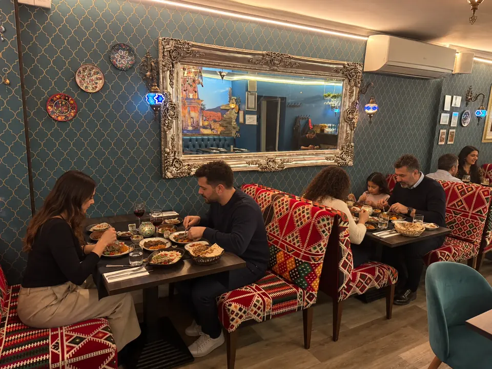 Couples at the kilim booths beneath a silver mirror