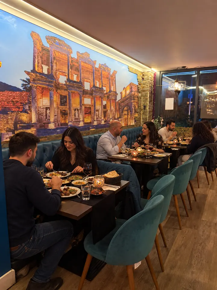 Diners along the banquette under the Ephesus library mural
