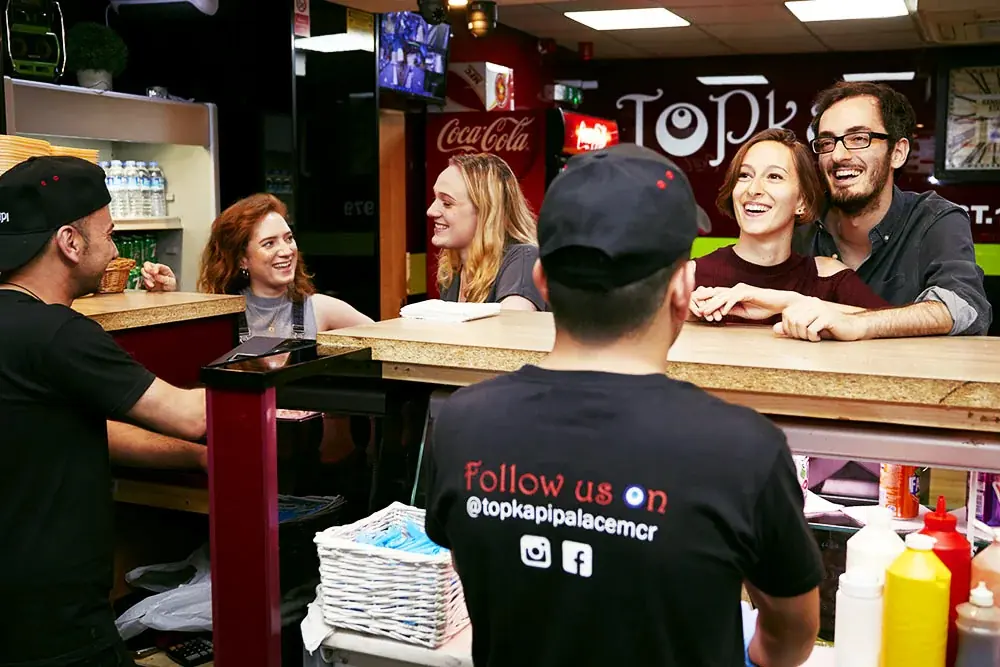 Customers laughing at the counter while the team serves them